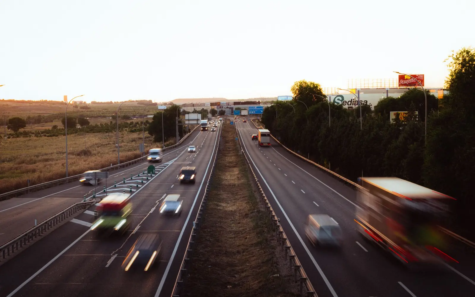 Traffic moving on a wide multi-lane highway at dusk